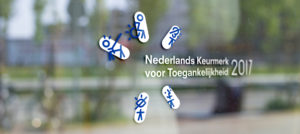 Afbeelding waar de sticker van het Nederlands Keurmerk voor Toegankelijkheid te zien is op een winkelruit.