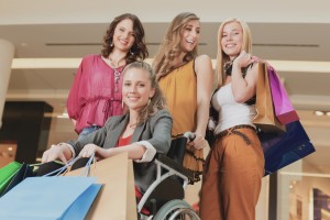 Foto van jonge meiden die aan het winkelen zijn waarvan er één in een rolstoel zit.